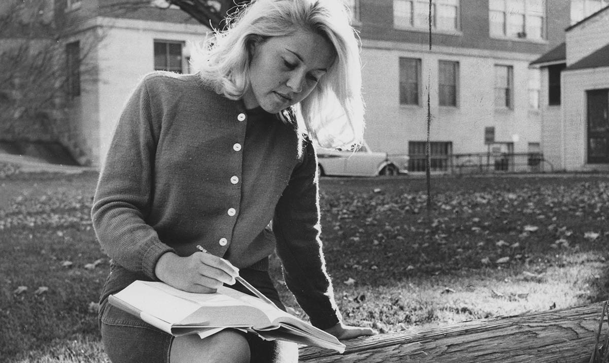 Woman studying outside Old Main with a book