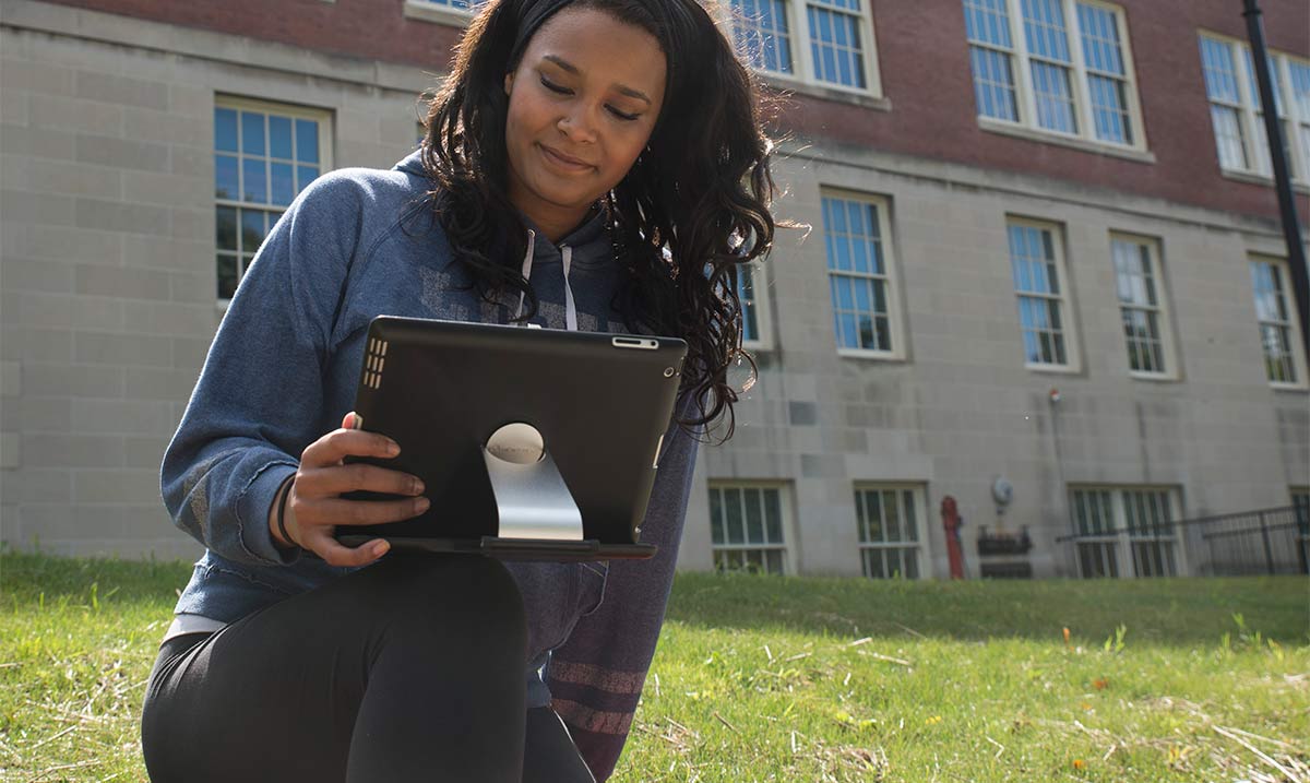 Woman studying outside Old Main with an iPad